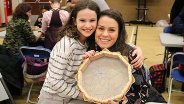 Female student poses with her mother showing the hand drum the student has created