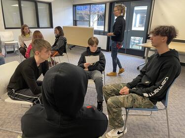 Group of 4 male students sitting in chairs in a circle