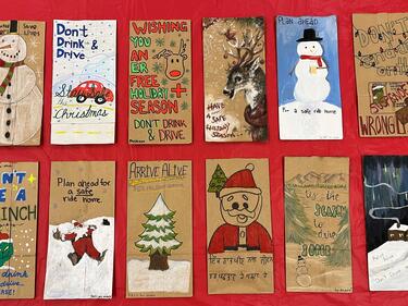 Paper bags laying flat on a red background. Bags have Christmas themed drawings on them.