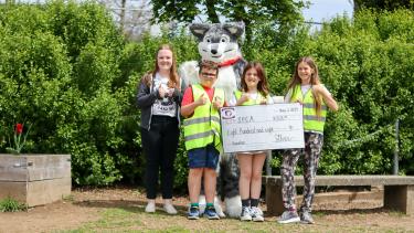 2024 SPCA Dance Donation by McMillan Elementary Student holding a large cheq with Husky mascot and local SPCA representative