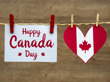 Canada Day sign and heart-shaped Canadian flag decoration hanging on a string with clothespins.