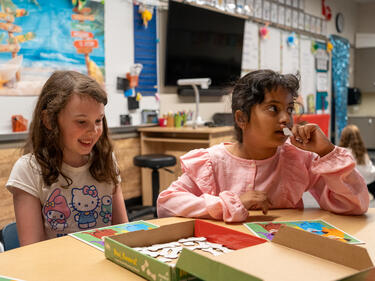 Two elementary girls sitting at a desk playing a game