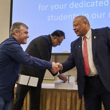 Dr. Kevin Godden shakes hands with male employee receiving long term service gift