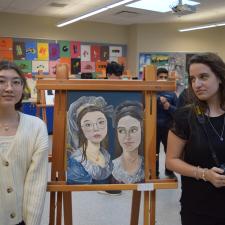 Students standing with their art on display for art show