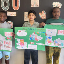 Three students holding poster projects