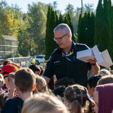 AbbyPD member holds box around a large group of students, handing out gifts.