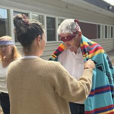Man being blanketed by a female in an Indigenous honouring