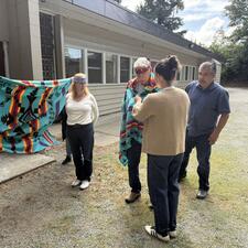 Small group of people working together to blanket two individuals for an Indigenous Honouring.