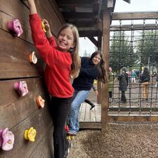 Two elementary students on a climbing wall and smiling at the person taking the photo.